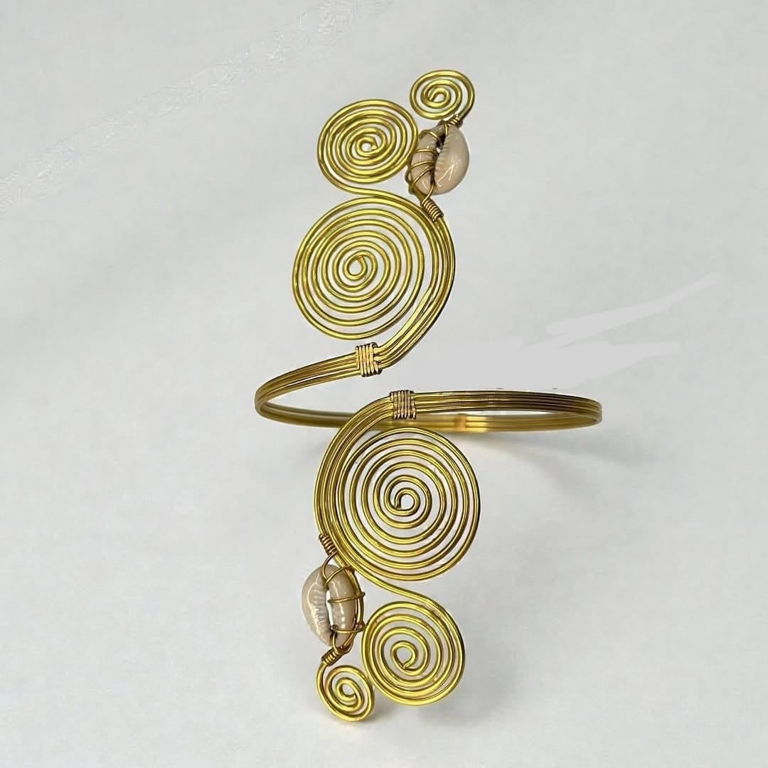 Brass gold-toned metal cuff bracelet featuring multiple spiral wire motifs and two small seashell accents