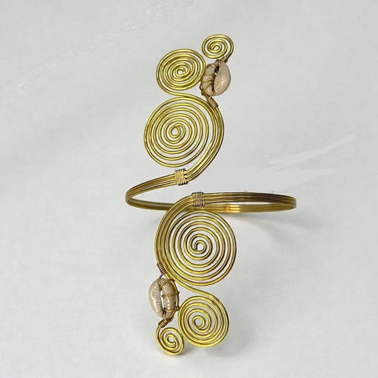 Brass gold-toned metal cuff bracelet featuring multiple spiral wire motifs and two small seashell accents