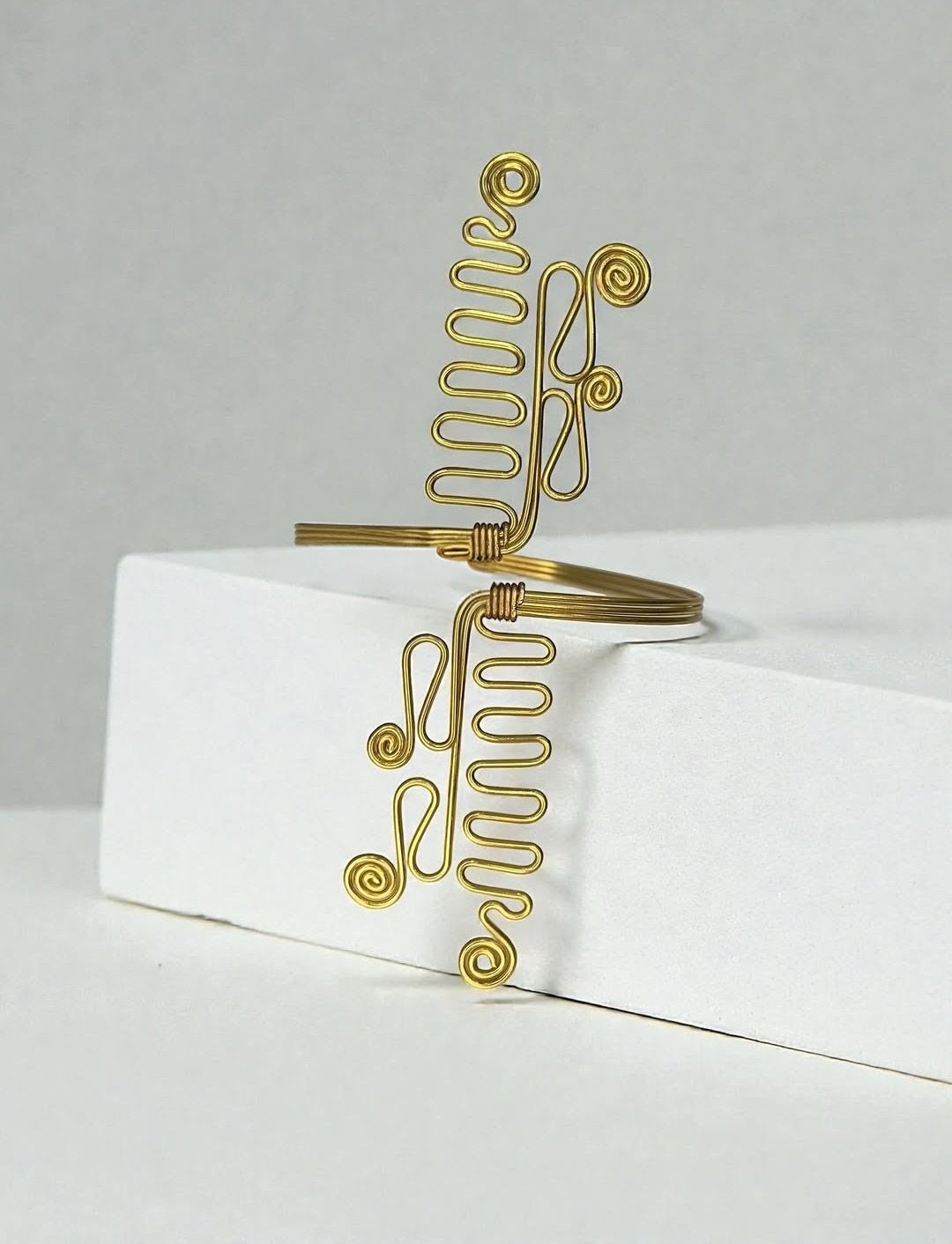 A Brass wire wrap cuff bracelet with spiral and coiled decorative details
